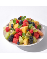 Close up of fruit salad made up of strawberries, blackberries, raspberries, blueberries, and peaches in a white stoneware bowl