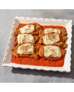 Oblique view of chicken parmigiano served in a white bowl, with a casserole dish of chicken parmigiano in the background