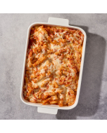 Overhead closeup of baked ziti served in a white ceramic bowl, garnished with a sprig of basil