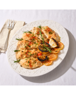 Oblique overhead view of chicken piccata in a white stoneware casserole dish