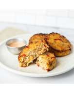 Oblique view of crabcakes served on a white stoneware plate, with a side of spicy tartar sauce