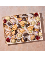Overhead view of miniature cannoli, miniature éclairs, pistachio glazed cream puffs, miniature sfogliatelle, ricotta cheesecake tart, pignoli cookies, chocolate-dipped Amaretti cookies, arranged in rows on a stone platter
