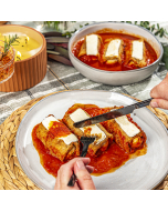 Oblique view of four eggplant rollatini in red sauce served on a rectangular white plate