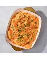 Overhead view of lobster ravioli smothered in a pink la rosa sauce, served in a white stoneware bowl and garnished with a spring of parsley.