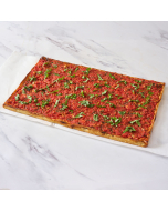 Overhead close-up of a corner piece of tomato pie, served on a bamboo cutting board
