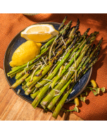 Overhead view of grilled asparagus, topped with parmigiano reggiano served on a wooden cutting board