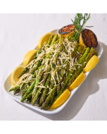 Overhead view of grilled asparagus, topped with parmigiano reggiano served on a wooden cutting board