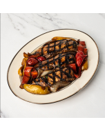 Oblique view of three grilled chicken breasts, nestled in roasted onion and peppers, and served on a white ceramic platter.