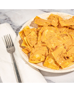 Overhead view of lobster ravioli smothered in a pink la rosa sauce, served in a white stoneware bowl and garnished with a spring of parsley.