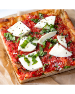 Overhead close-up of a corner piece of margherita pie, served on a platter on butcher paper