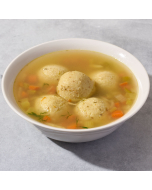 Overhead view of matzo ball soup served in a white scalloped bowl
