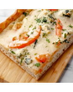 Close-up overhead view of an edge piece of square white pizza topped with sliced tomatoes, spinach, and ricotta cheese