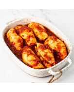 Six stuffed shells in red sauce, served in a white speckled stoneware casserole dish