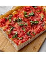 Overhead close-up of a corner piece of tomato pie, served on a bamboo cutting board