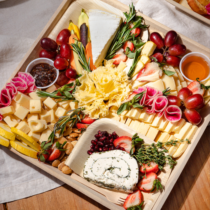 Connoisseur's Choice Cheese board artisanal cheeses sliced and arranged with assorted spreads fresh fruit and herbs