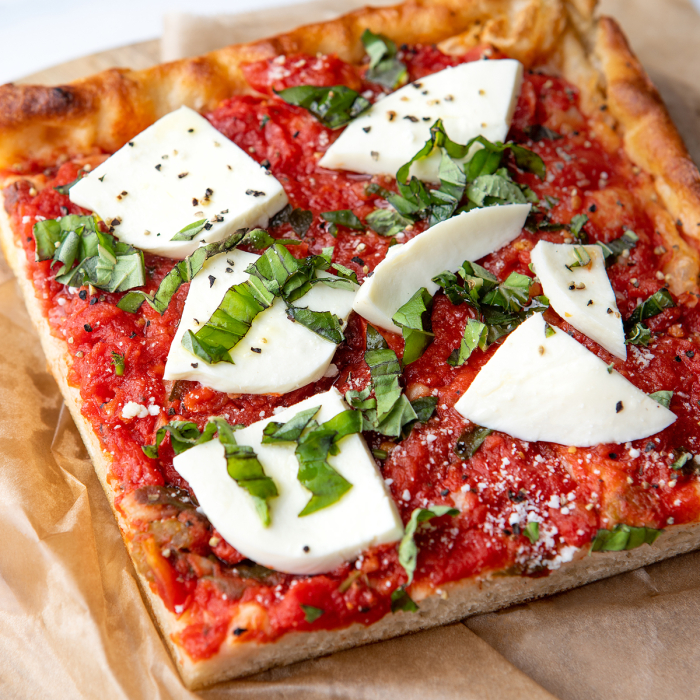 Overhead close-up of a corner piece of margherita pie, served on a platter on butcher paper