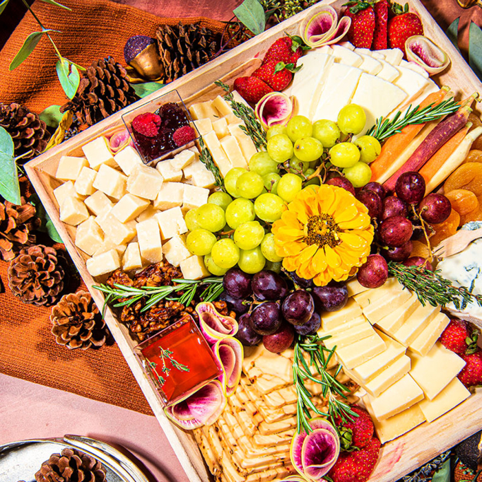 Overhead shot of decoratively arranged cheese tray with white cheese cubes, grapes, and strawberries