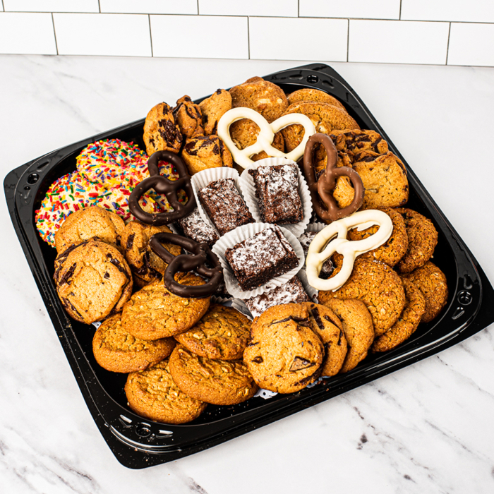 Overhead view of various sweets arranged in a black plastic serving tray.  Including chocolate covered pretzels, miniature brownies, chocolate chip cookies, peanut butter cookies, oatmeal cookies, and sugar cookies